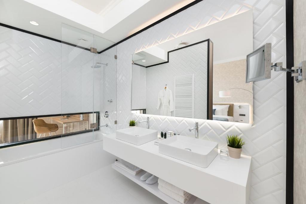 a white bathroom with two sinks and a mirror at Hotel Vision Budapest by Continental Group in Budapest