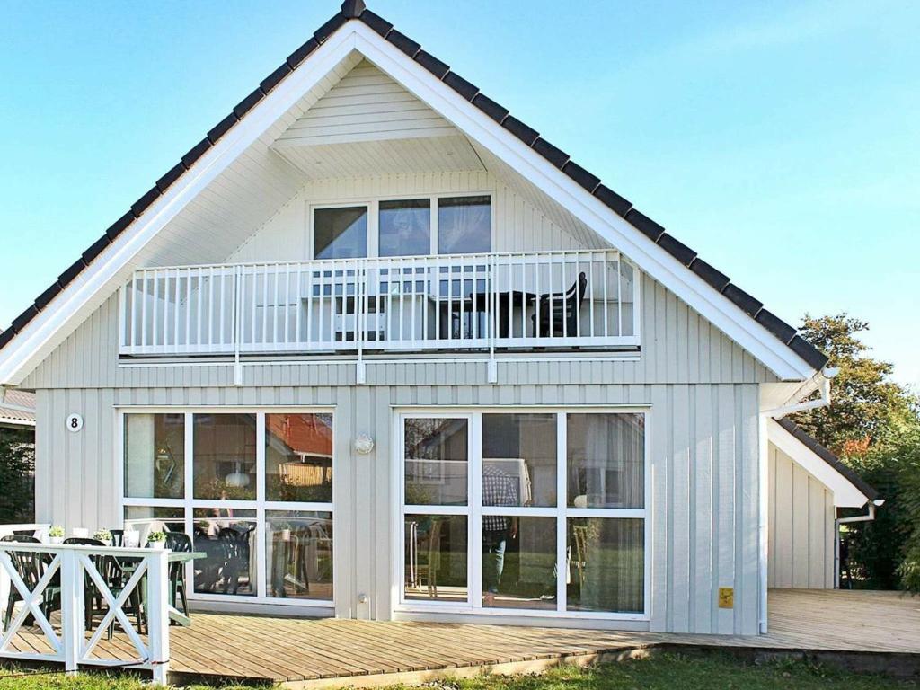 ゲルティングにあるThree-Bedroom Holiday home in Gelting 7のバルコニーとデッキ付きのホワイトハウスです。