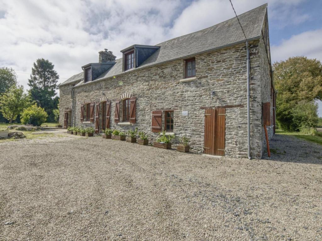 una antigua casa de piedra con una entrada de grava en Enticing Holiday Home in Berigny with Swimming Pool en Bérigny