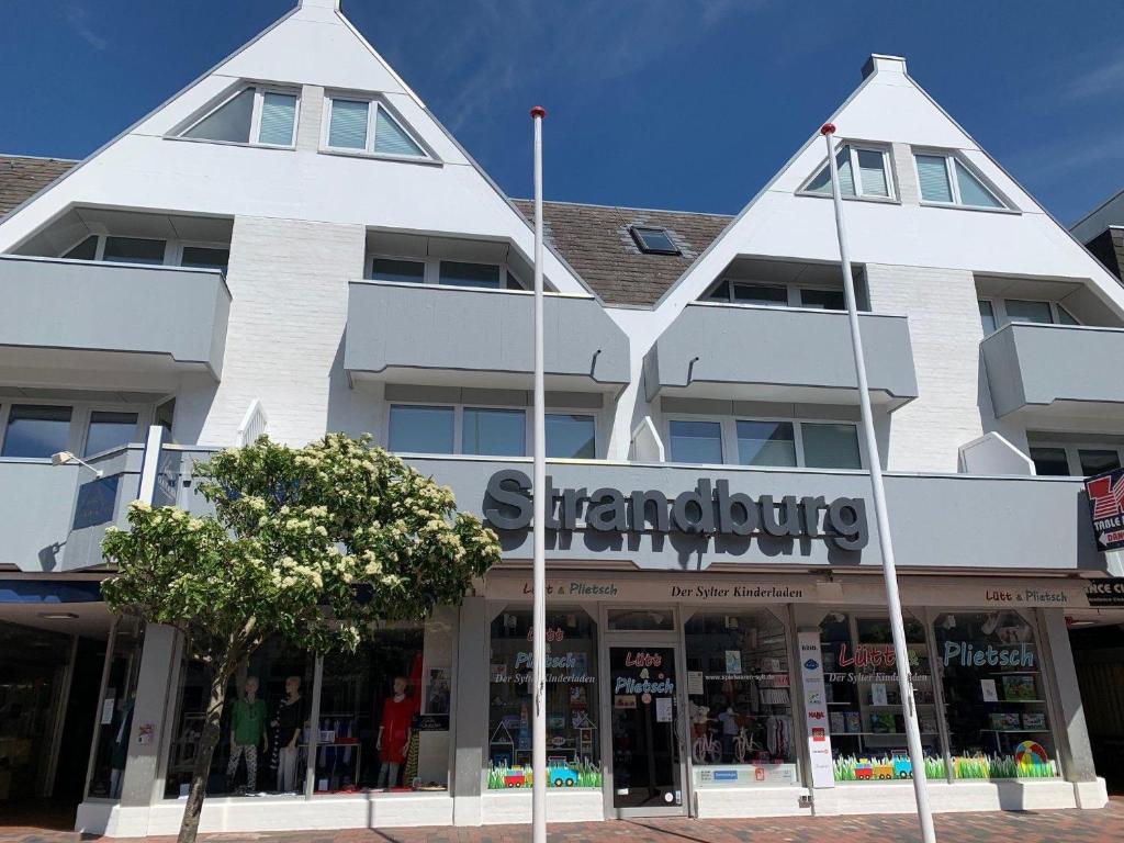 Ein weißes Gebäude mit einem Laden davor. in der Unterkunft Haus Strandburg, Wohnung17, 25980 Westerland in Westerland