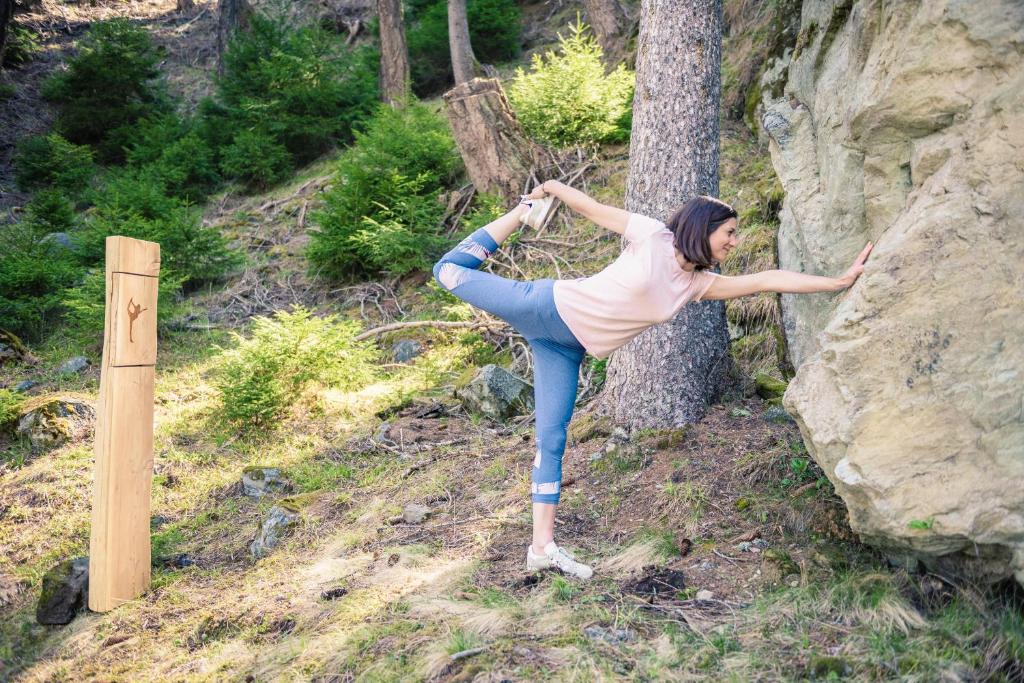 a woman doing a handstand on the side of a rock at Hôtel Magrappé in Veysonnaz