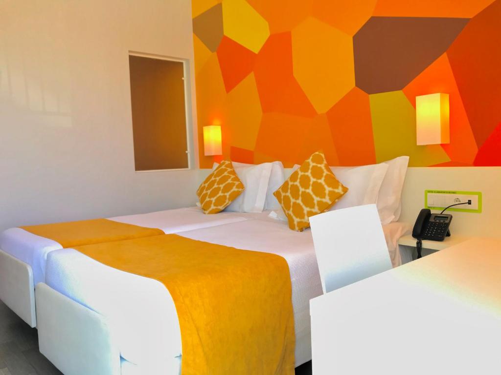 a bedroom with two beds and a colorful wall at Hotel 3K Faro Aeroporto in Faro