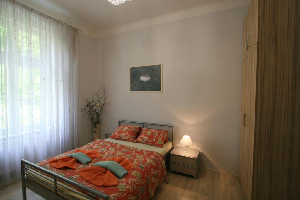 une chambre avec un lit avec des draps orange et une fenêtre dans l'établissement Apartment No 21 - I P Pavlova 34, à Karlovy Vary