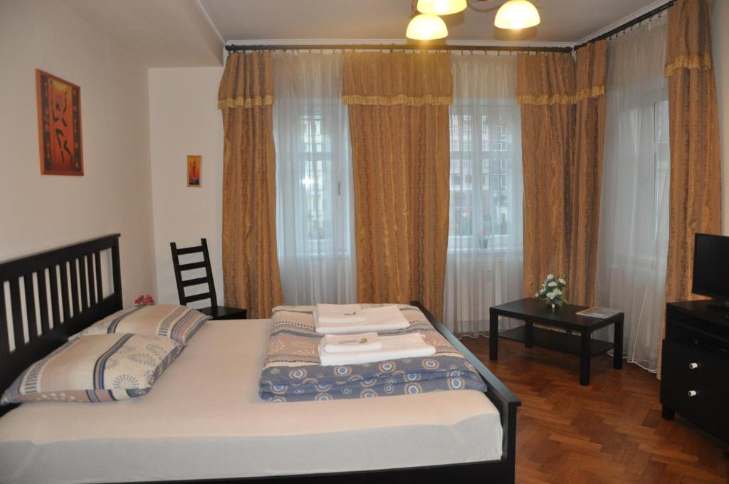 1 dormitorio con cama, TV y cortinas en Apartment No. 40 Stará louka 20, en Karlovy Vary