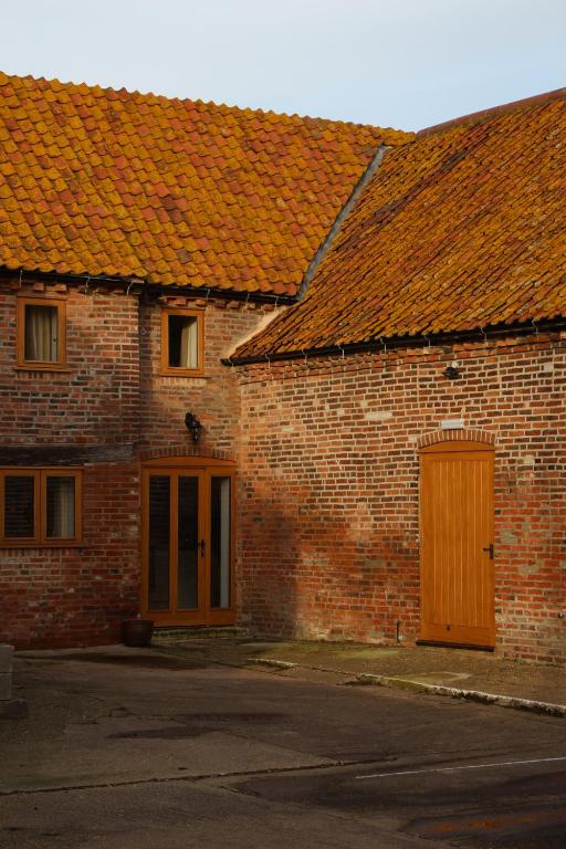 a brick building with orange roofs and two doors at The HopBarn in Hockerton