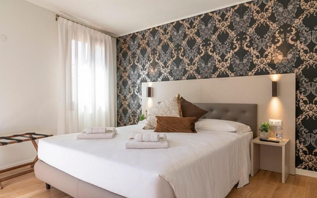 a bedroom with a large bed with two towels on it at Grifoni Boutique Hotel in Venice