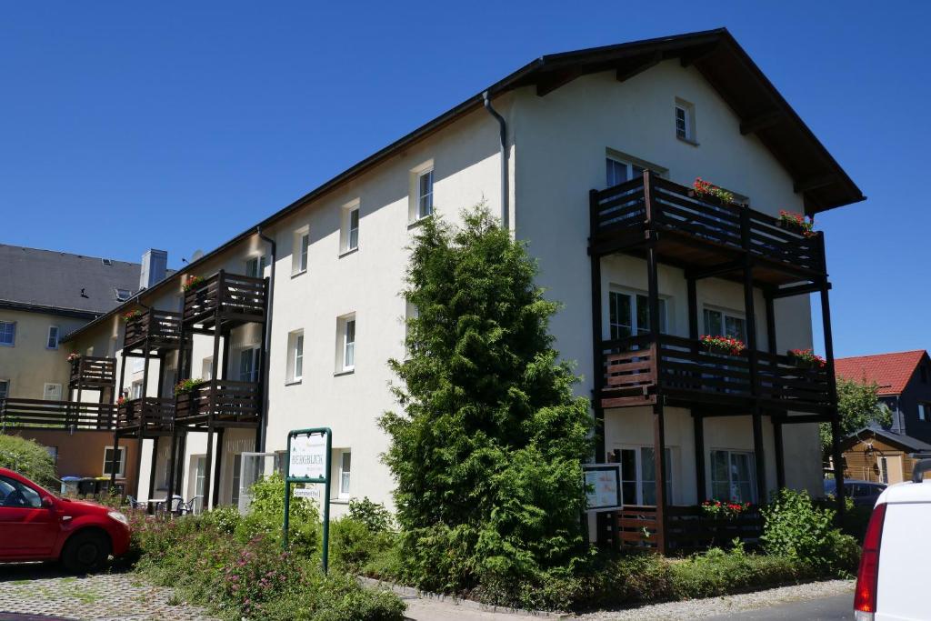 ein großes weißes Gebäude mit Balkonen und einem roten Auto in der Unterkunft Haus Bergblick in Frauenwald