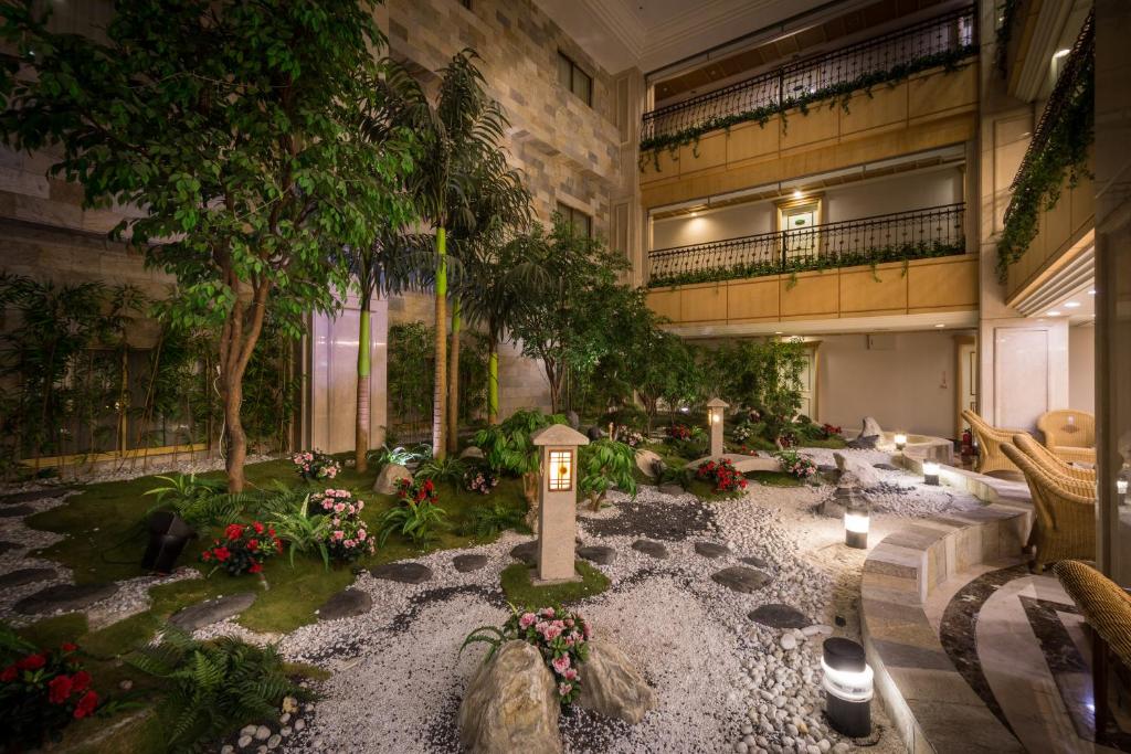 Guide Hotel Zhongli Zhongzheng في تشونغلي: مبنى كبير به حديقة بها الزهور والنباتات