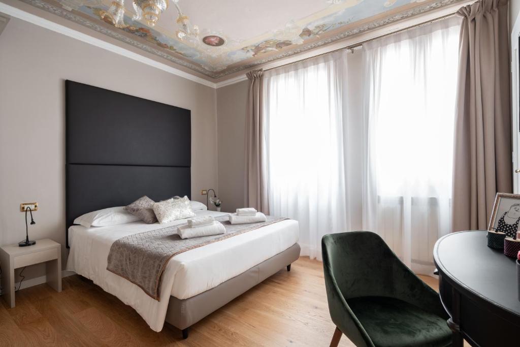 - une chambre avec un grand lit et une chaise dans l'établissement Locanda Herion, à Venise