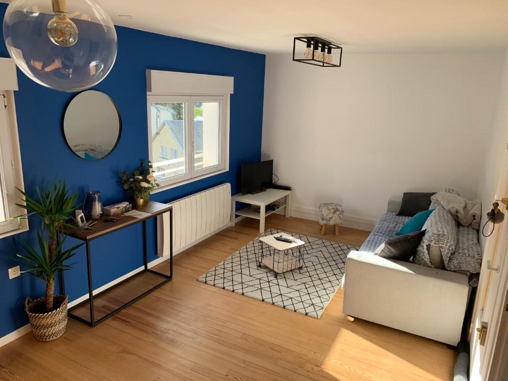 ein Wohnzimmer mit blauen Wänden und einem weißen Sofa in der Unterkunft Duplex plein centre ville 3Etoiles in Le Mont-Dore