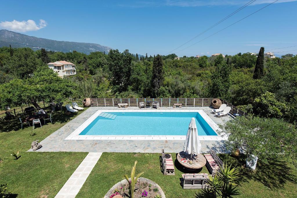 einen Pool in einem Garten mit Stühlen und einem Sonnenschirm in der Unterkunft Adonis Villa in Dassia