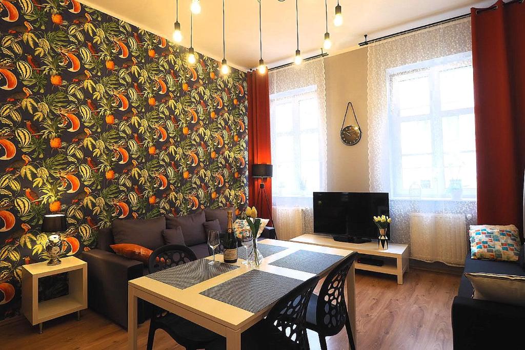 uma sala de estar com uma mesa e uma parede com abóboras em KGHN Apartments Tkacka 11 em Szczecin