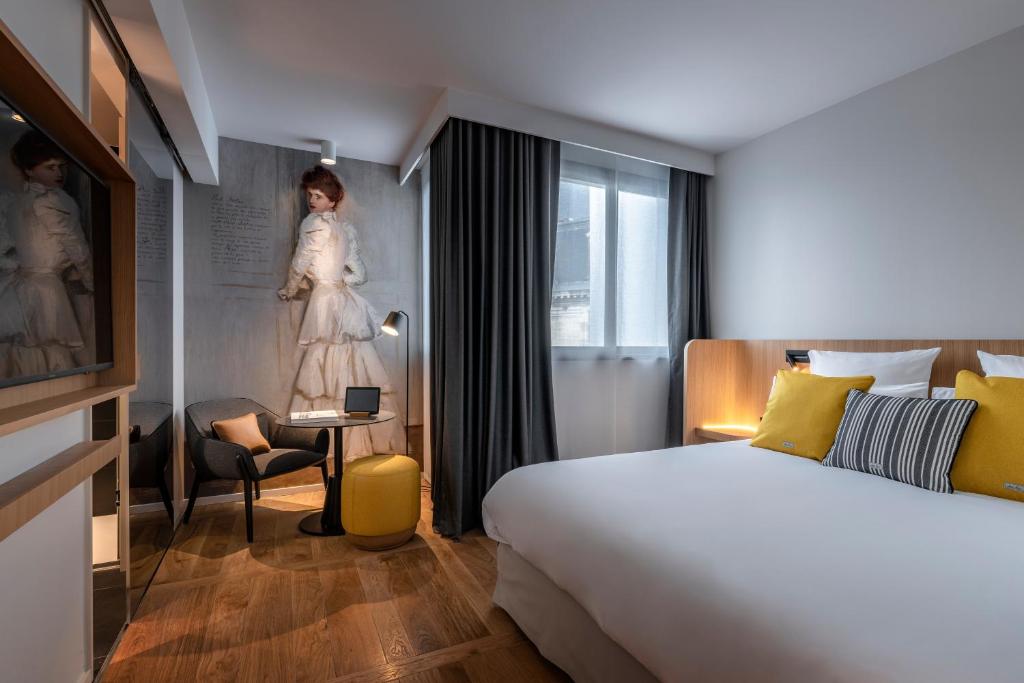 a hotel room with a bed and a woman on the wall at Hôtel Villa KOEGUI Bayonne in Bayonne