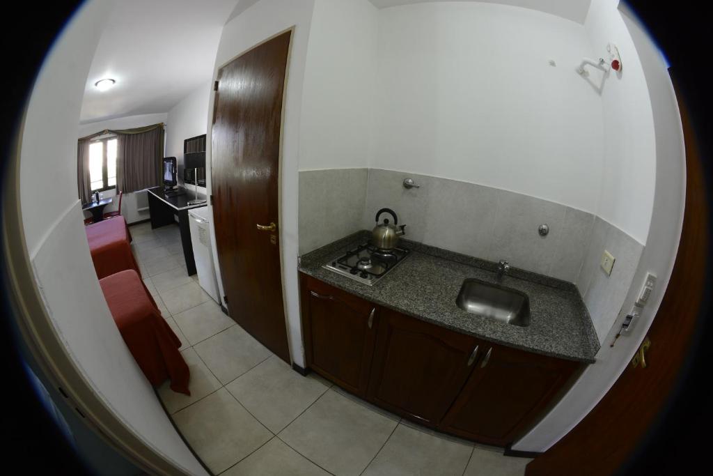 a view of a kitchen with a sink and a living room at Apart Hotel Alvear in Rosario