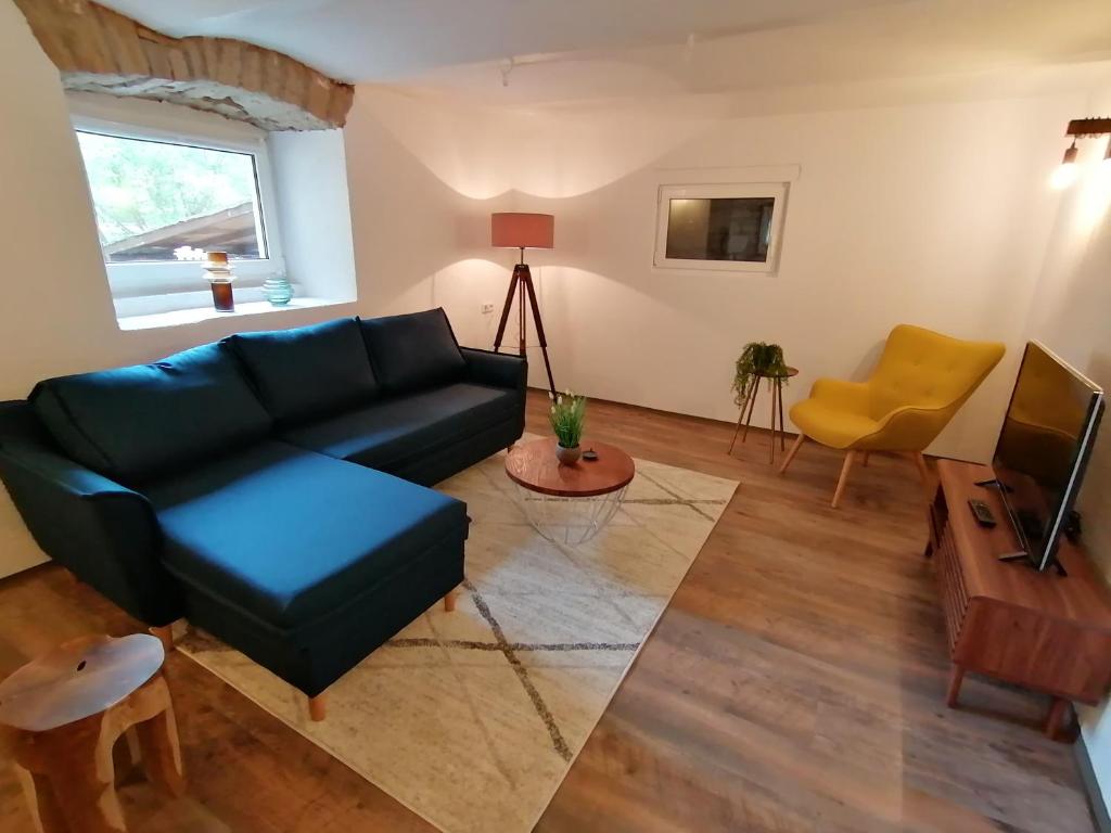a living room with a black couch and a yellow chair at Creek Inn, Contactless Check-in in Glanbrücken