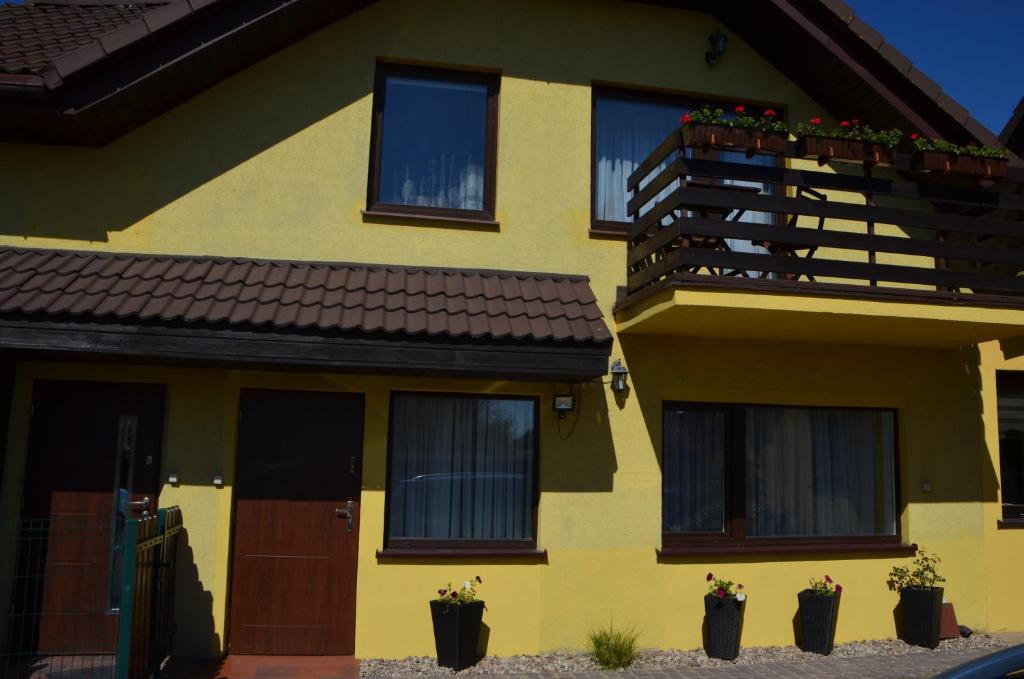ein gelbes Haus mit einem Balkon und Topfpflanzen in der Unterkunft Apartament Słoneczny in Danzig