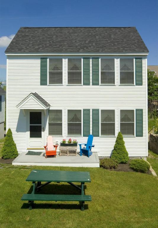 a house with two chairs and a picnic table in the yard at Heron Neck Cottage at One Long Beach in York Beach
