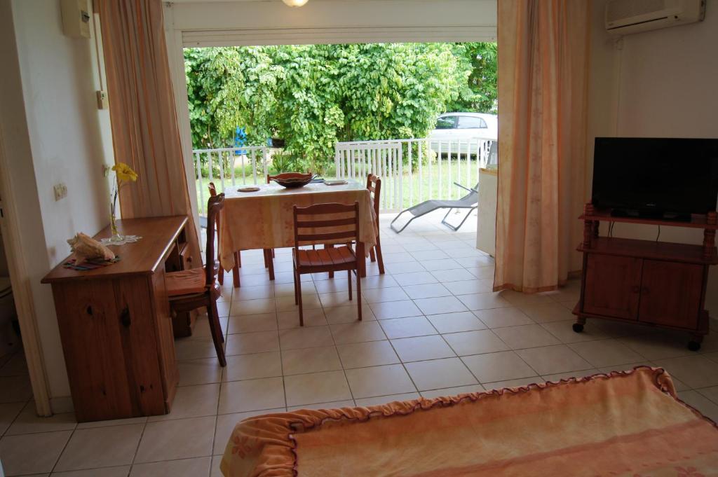 sala de estar con mesa, sillas y TV en Studio avec jardin clos et wifi a Le Moule a 3 km de la plage, en Le Moule