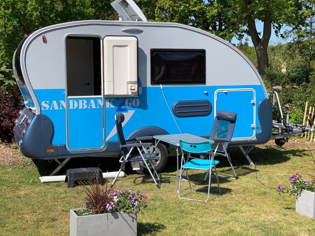 einem blau-weißen Wohnwagen mit einem Tisch und Stühlen in der Unterkunft Sandbank2go in Cuxhaven