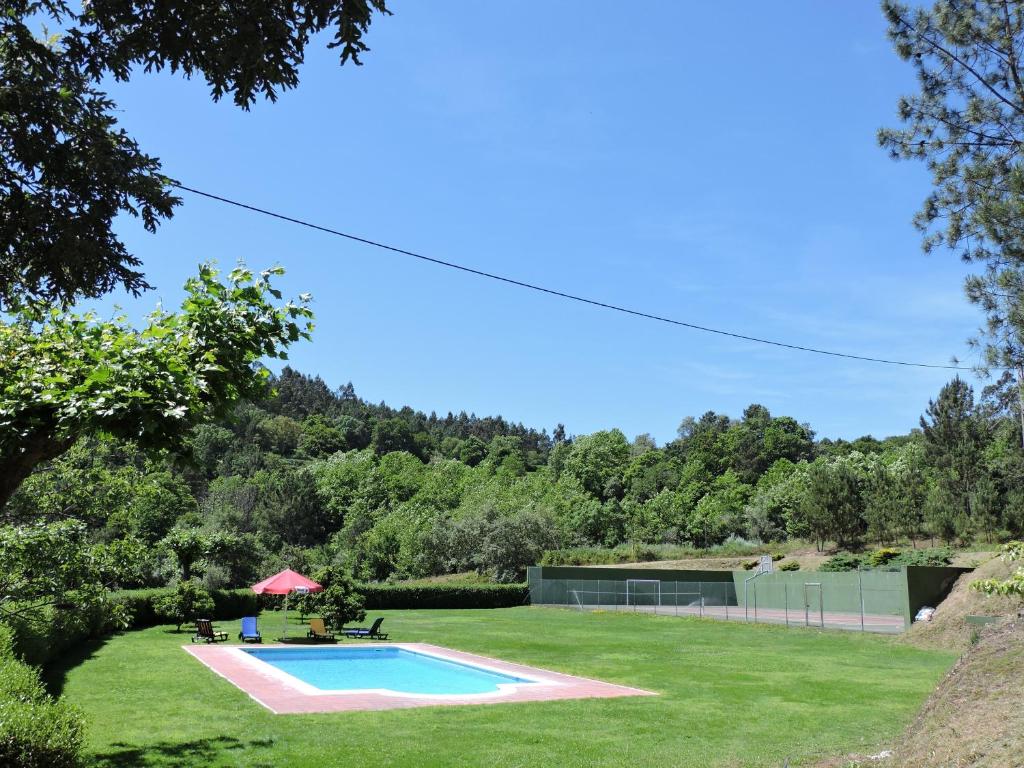 a swimming pool in the middle of a grass field at Casa das Vessadas in Celorico de Basto
