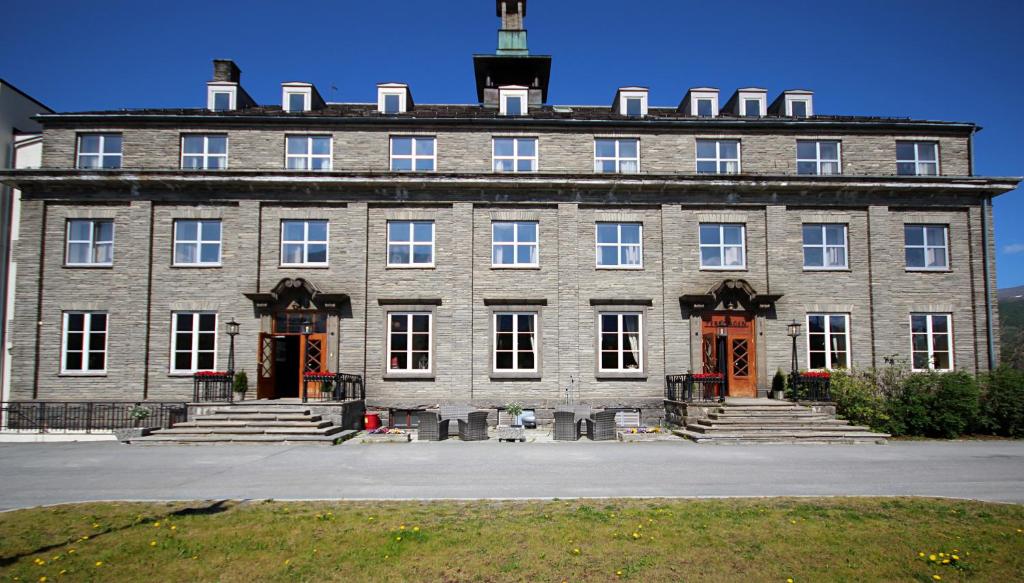 Un grand bâtiment en briques avec un escalier se trouve devant. dans l'établissement Oppdal Turisthotell, à Oppdal