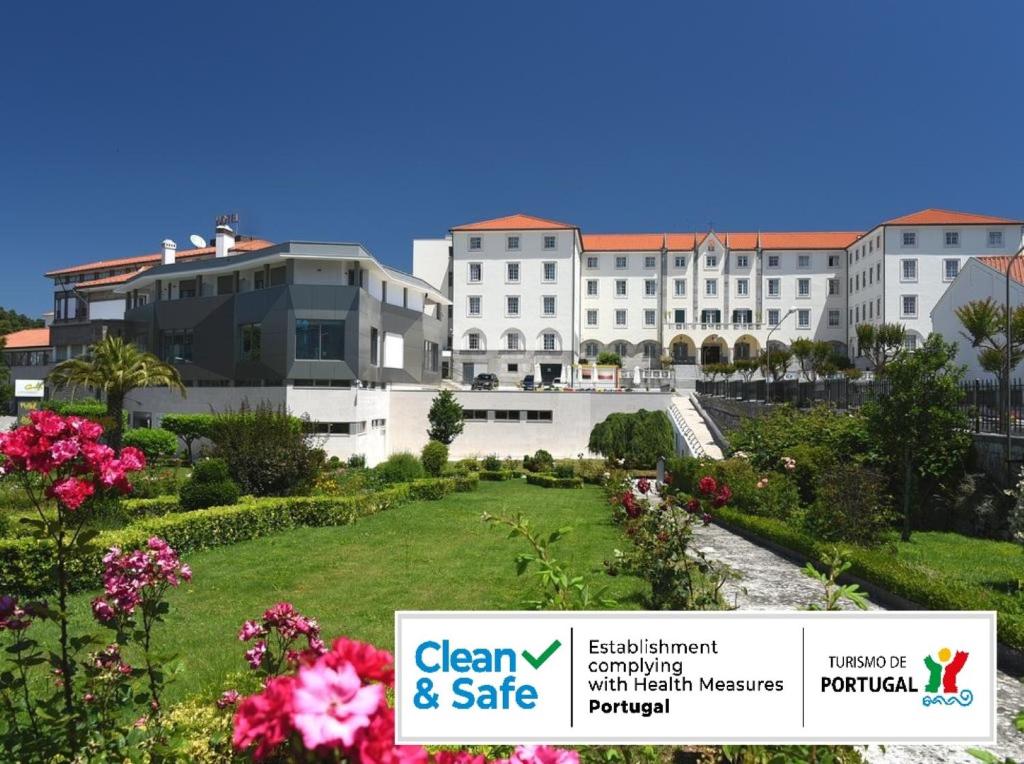 Elle offre une vue sur un grand bâtiment blanc doté d'un jardin. dans l'établissement Consolata Hotel, à Fátima