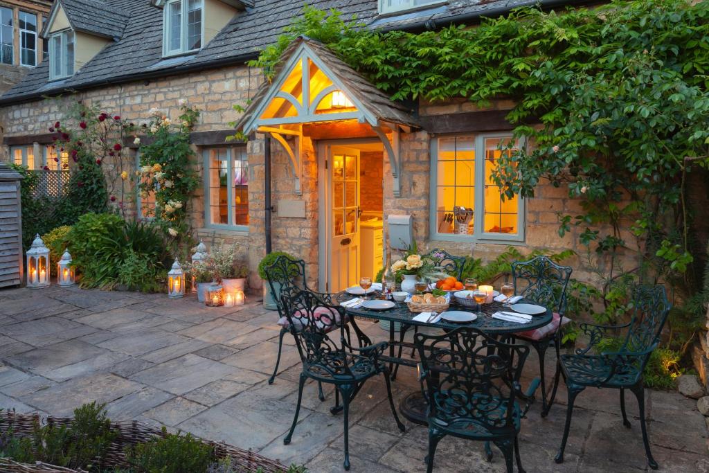 a patio with a table and chairs in front of a house at Hook Cottage in Chipping Campden