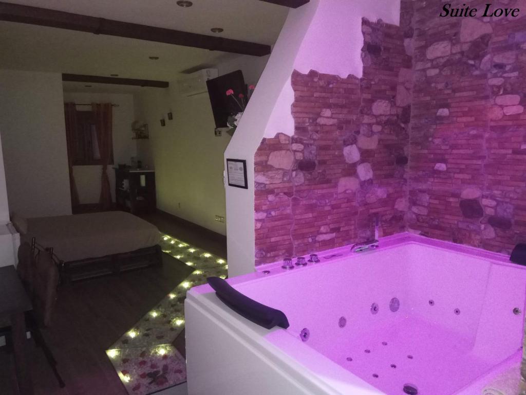 bañera rosa en una habitación con pared de ladrillo en Suite Love Jacuzzi (Casas Toya), en Uceda