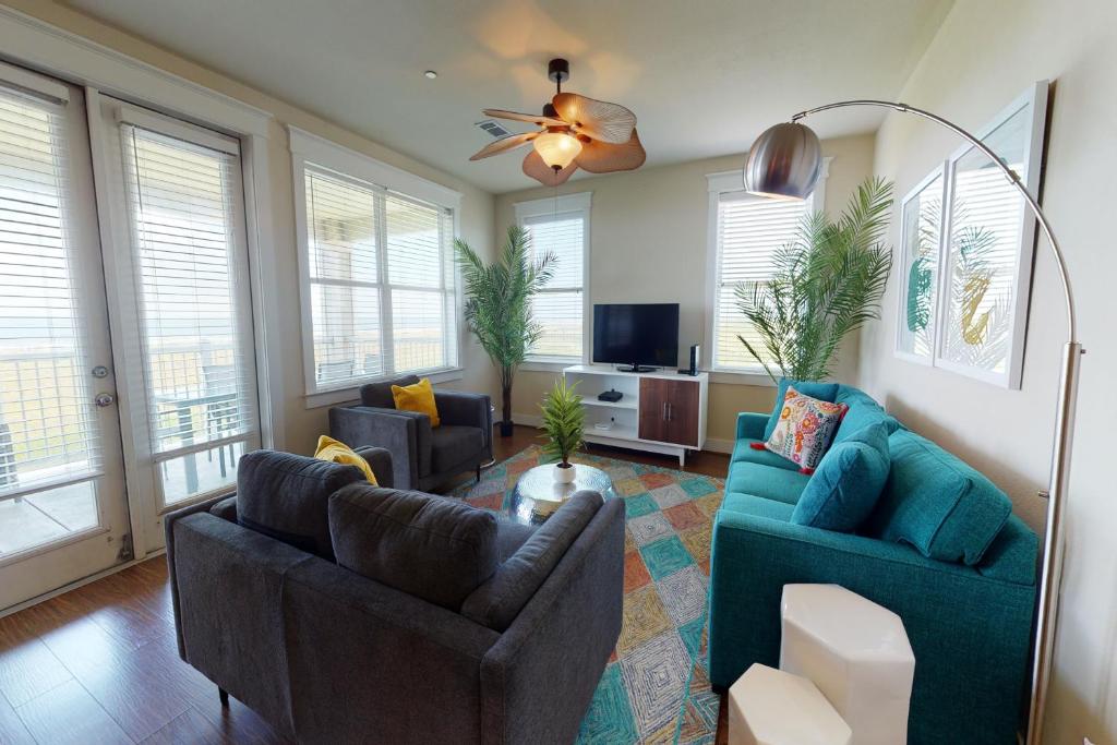 uma sala de estar com dois sofás azuis e uma televisão em Ocean Breeze em Galveston