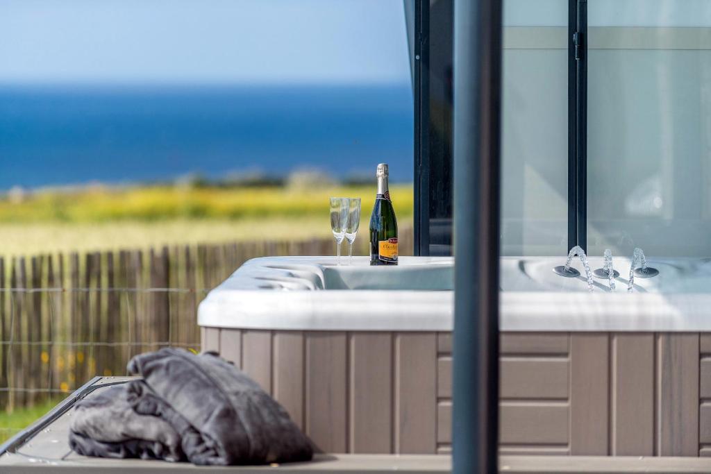 La salle de bains est pourvue d'un lavabo et d'une bouteille de vin. dans l'établissement La maison des gardiens de l'Océan avec spa - gite plougonvelin, à Plougonvelin