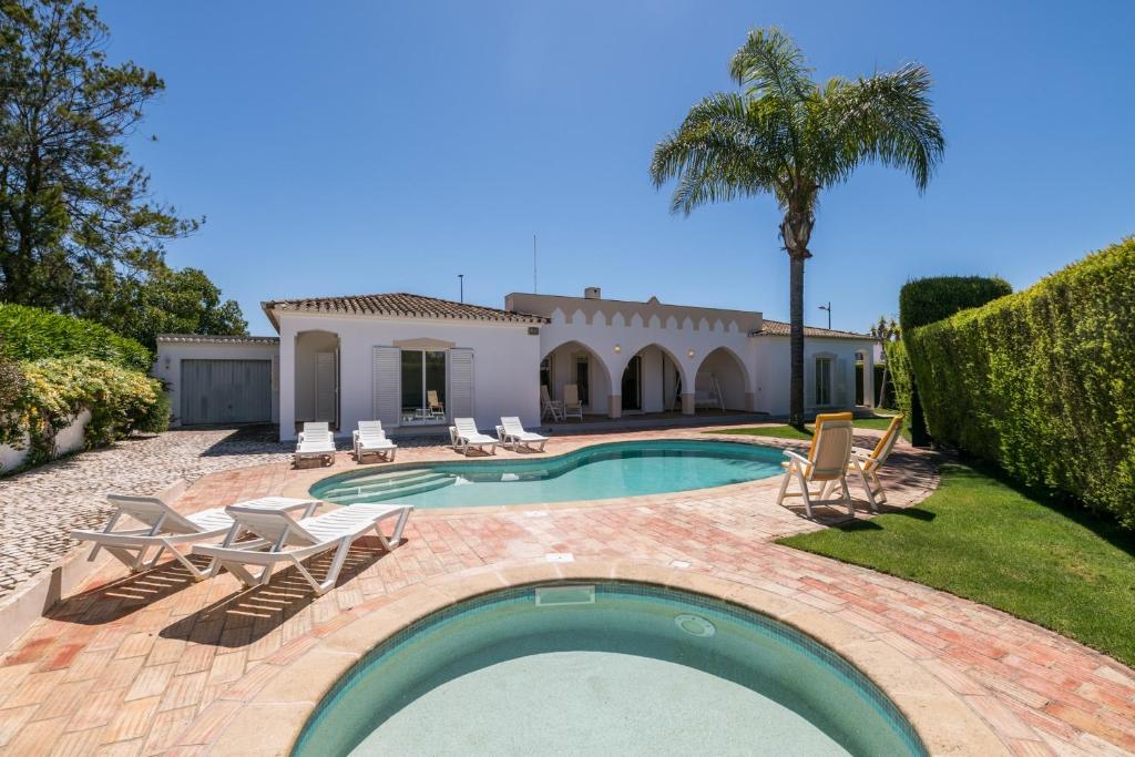 a swimming pool with chairs and a house at Quinta da Caldeira - Villa com piscina a 5 minutos a pé da praia in Lagos