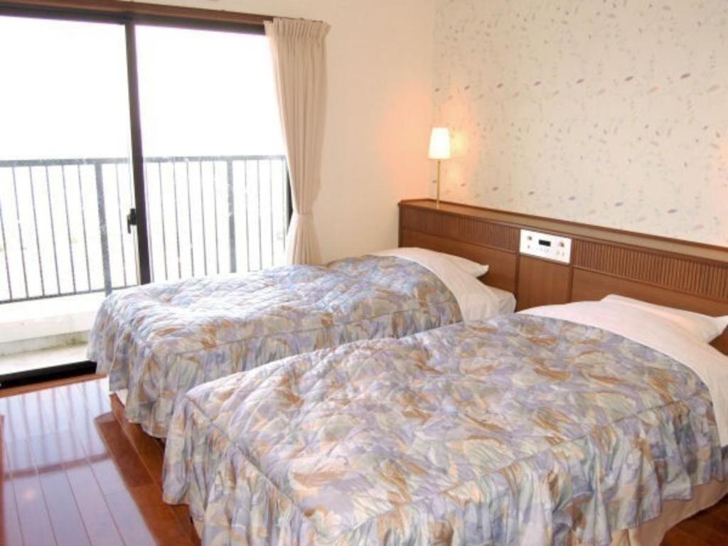 ein Hotelzimmer mit 2 Betten und einem Fenster in der Unterkunft Amami Resort Bashayamamura - Vacation STAY 81974 in Amami