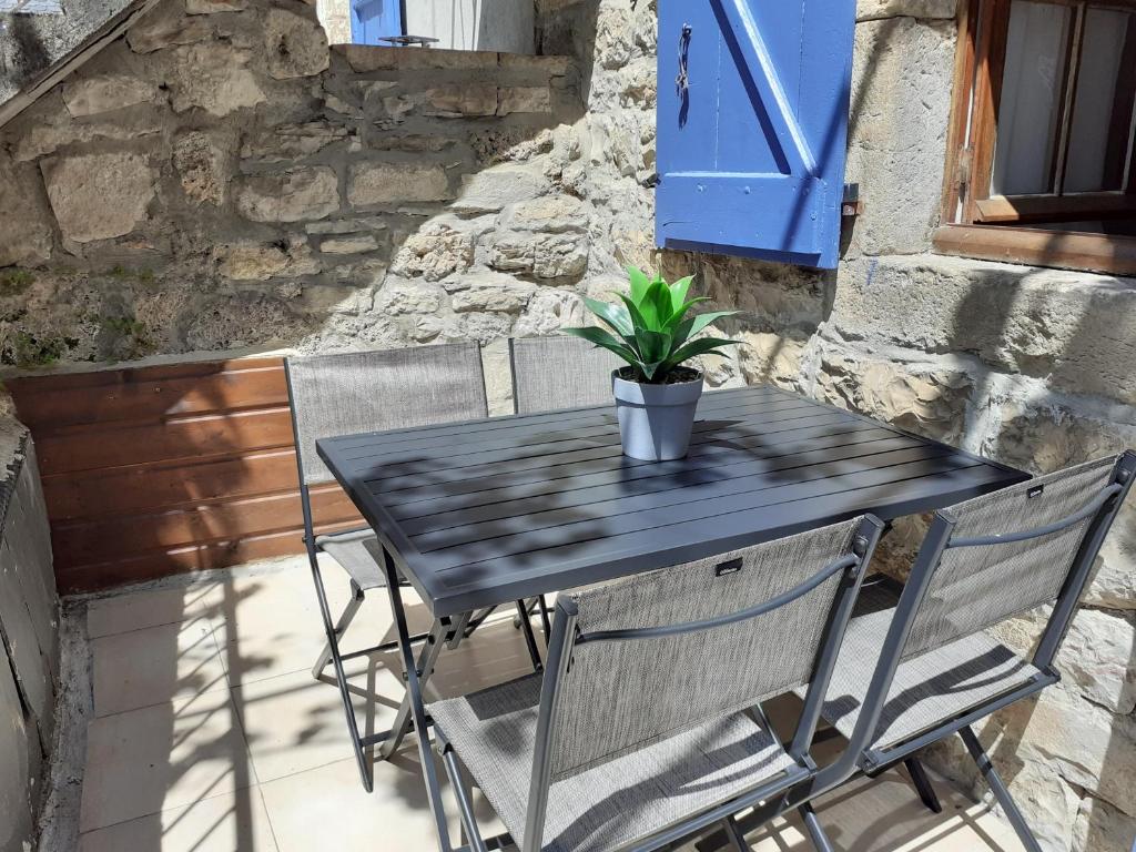 - une table noire avec deux chaises et une plante en pot dans l'établissement La maison d'Arnal, à Sainte-Énimie
