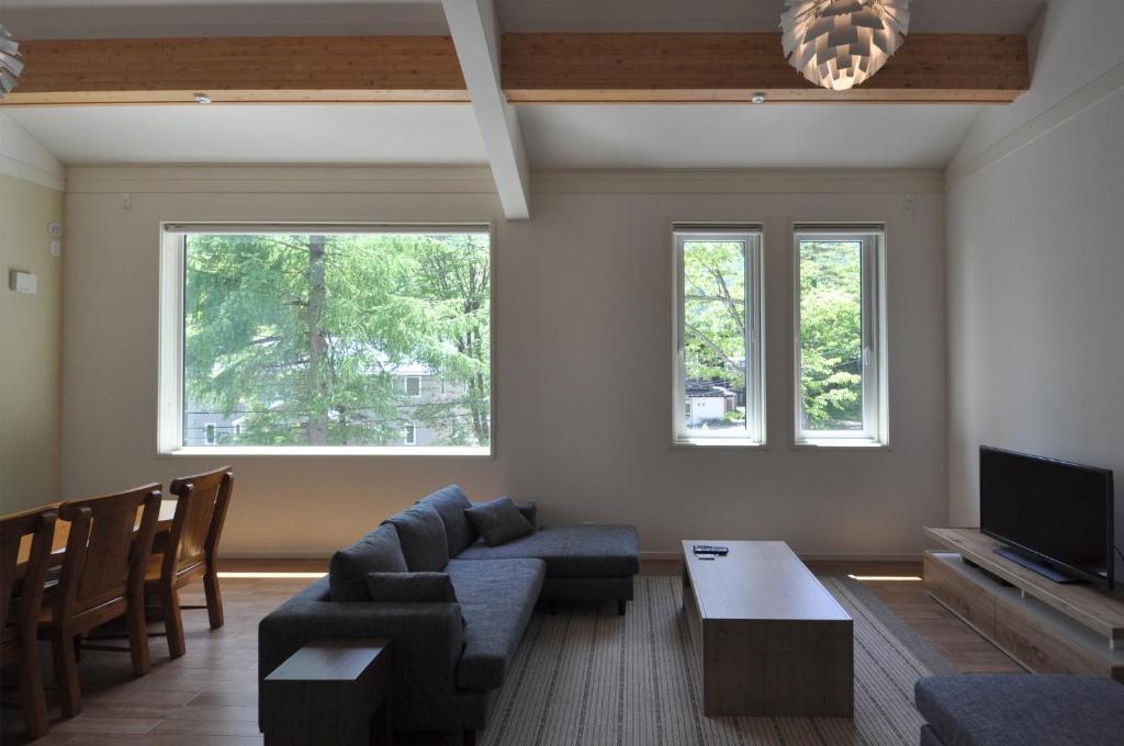 ein Wohnzimmer mit einem Sofa, einem TV und 2 Fenstern in der Unterkunft Cat's Villa Hakuba 4- Vacation STAY 82229 in Hakuba