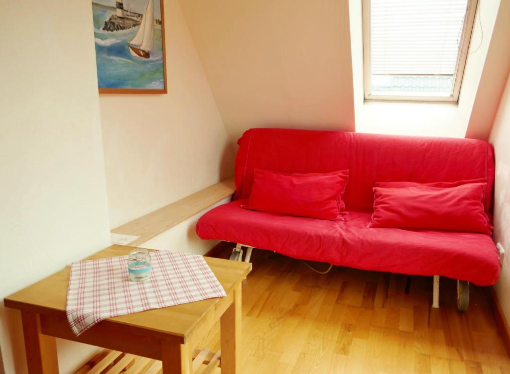 Öko-Ferienwohnung-Kiel Lachmöwe في كيل: أريكة حمراء في غرفة صغيرة مع طاولة
