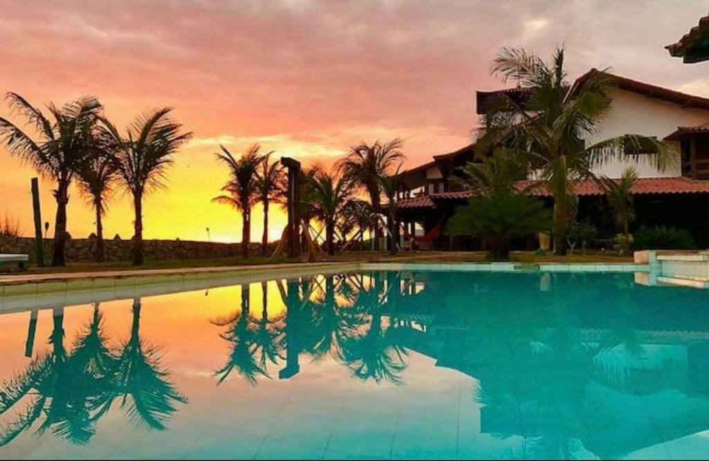 - une piscine avec des palmiers et un coucher de soleil dans l'établissement Oceanica 1000 Beachfront Suites, à Saquarema