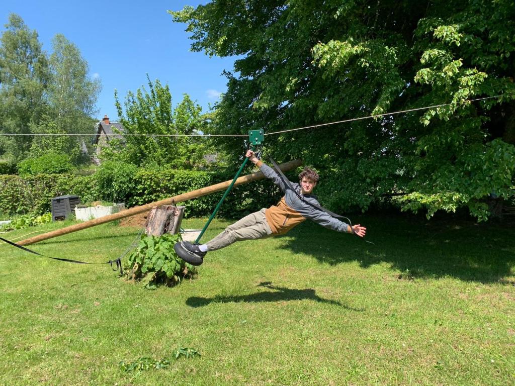 a young man is jumping on a zip line at Gîte de 15 places en chambre de 2, 4, 5 personnes in Saint-Exupéry-les-Roches