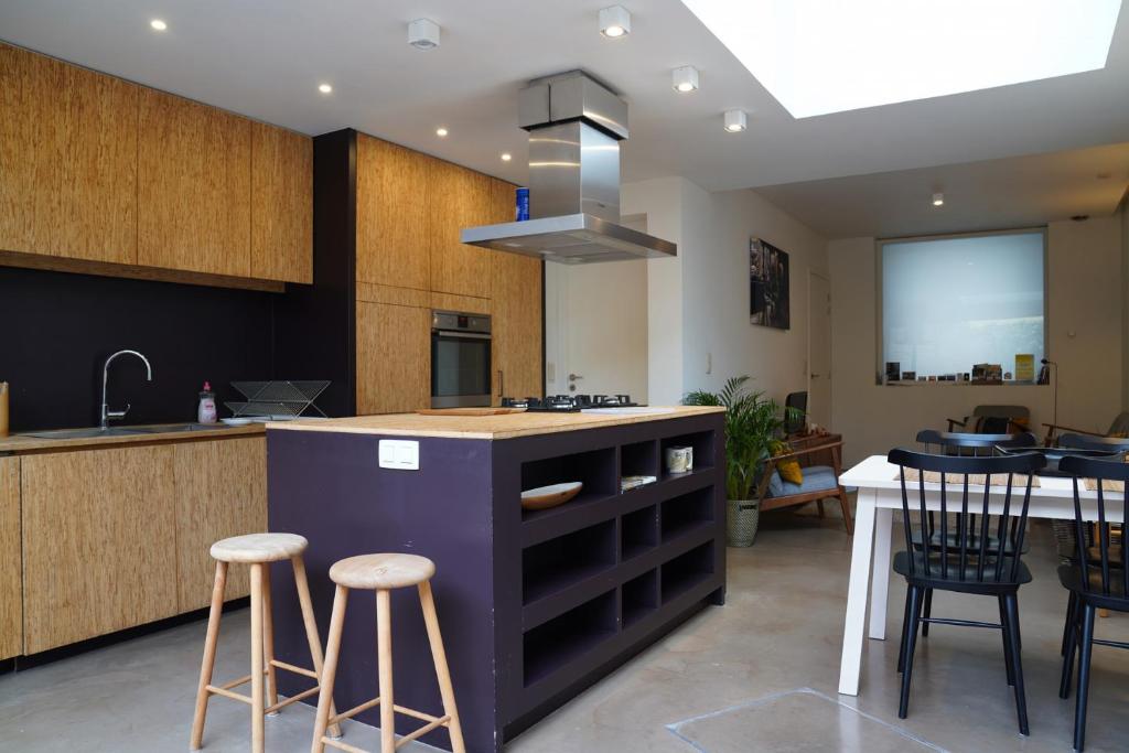 a kitchen with a island with bar stools and a table at Well-situated and Comfortable Home in Ghent