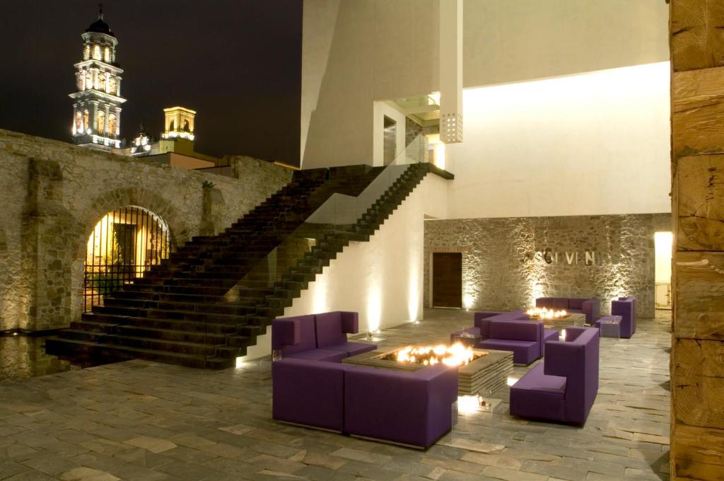 a room with purple chairs and stairs with a clock tower at La Purificadora, Puebla, a Member of Design Hotels in Puebla