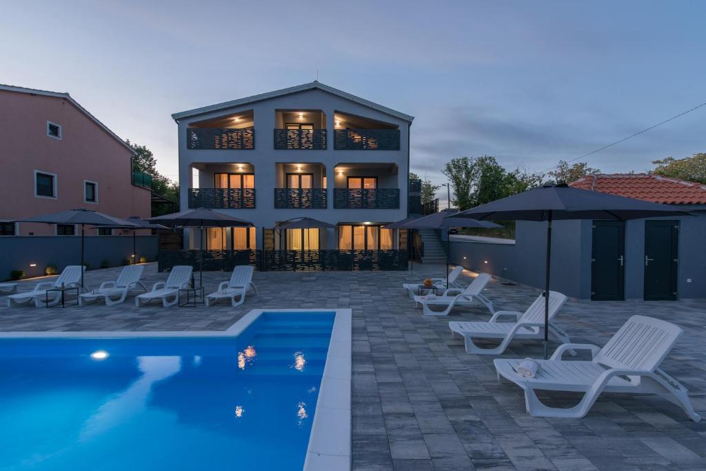 a house with a swimming pool and chairs and a building at Apartmani Natalija in Poreč