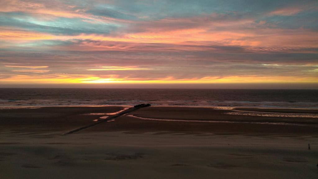 ein Sonnenuntergang am Strand mit einem Auto auf dem Sand in der Unterkunft Knappe studio met subliem zeezicht! in Ostende