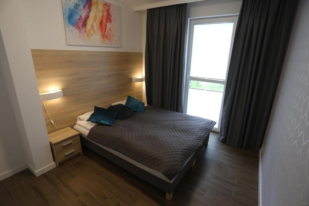 una camera da letto con un letto con cuscini blu e una finestra di Apartamenty MGM Legionowo a Legionowo