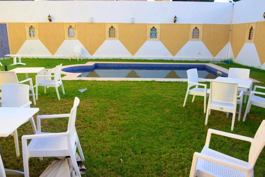a group of white chairs and tables and a pool at 5 bedrooms villa at Monastir 200 m away from the beach with private pool enclosed garden and wifi in Monastir