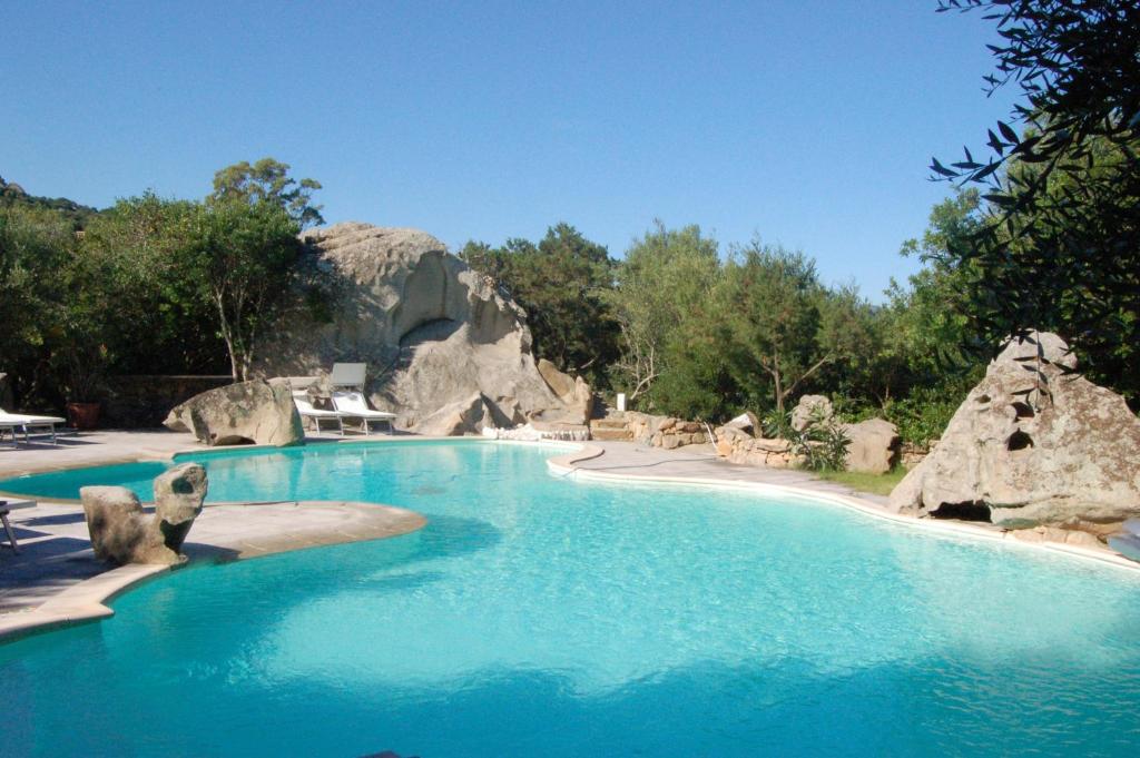 a large swimming pool with blue water and rocks at Charming Studio in Olbia with Garden, 35 m² in Porto Rotondo