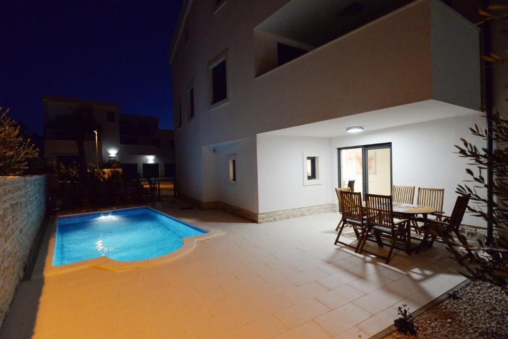 a patio with a swimming pool and a table and chairs at Apartment Nata - free parking in Murter