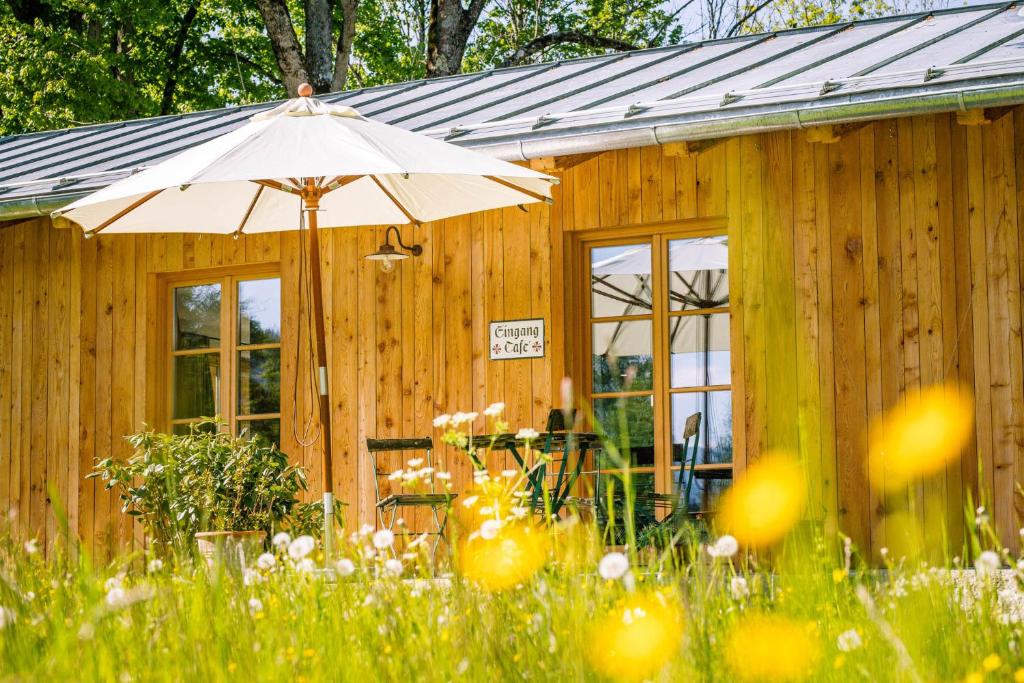 un bâtiment en bois avec un parasol dans l'herbe dans l'établissement Alpenchalet Kogel, à Bad Tölz