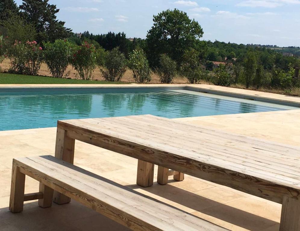 eine Holzbank vor einem Pool in der Unterkunft Villa de 6 chambres avec piscine privee jardin amenage et wifi a Cahors in Cahors