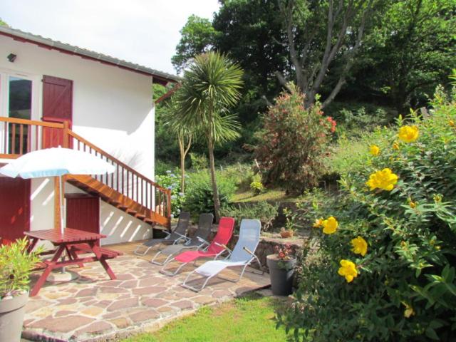 - une terrasse avec une table, des chaises et des fleurs dans l'établissement GITE IBARLA BORDA, à Bidarray