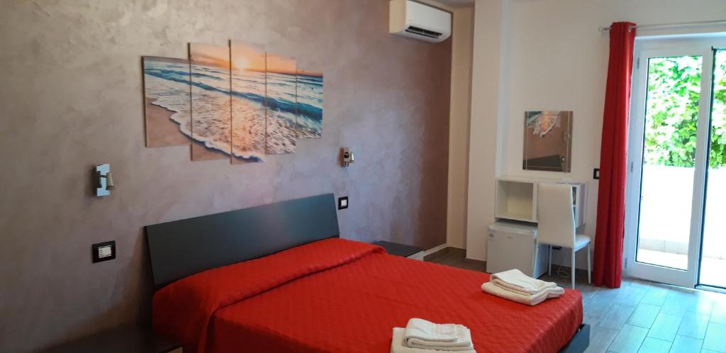 a bedroom with a red bed and a painting on the wall at Valeri 's Country House in Sperlonga
