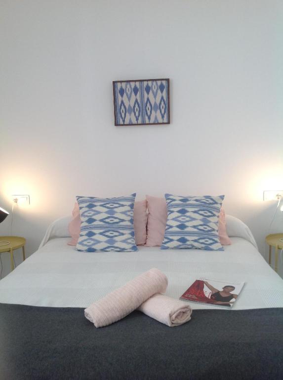 a bed with blue and white pillows and a book on it at PINK LEMON apartments in Córdoba